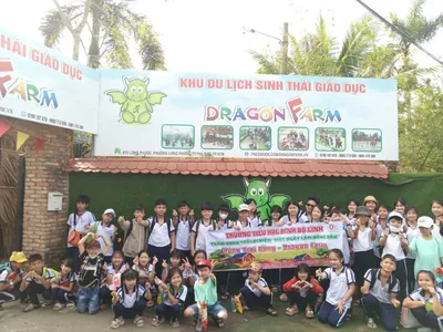 Các bé mầm non áo cam rạng rỡ check-in trước cổng nông trại