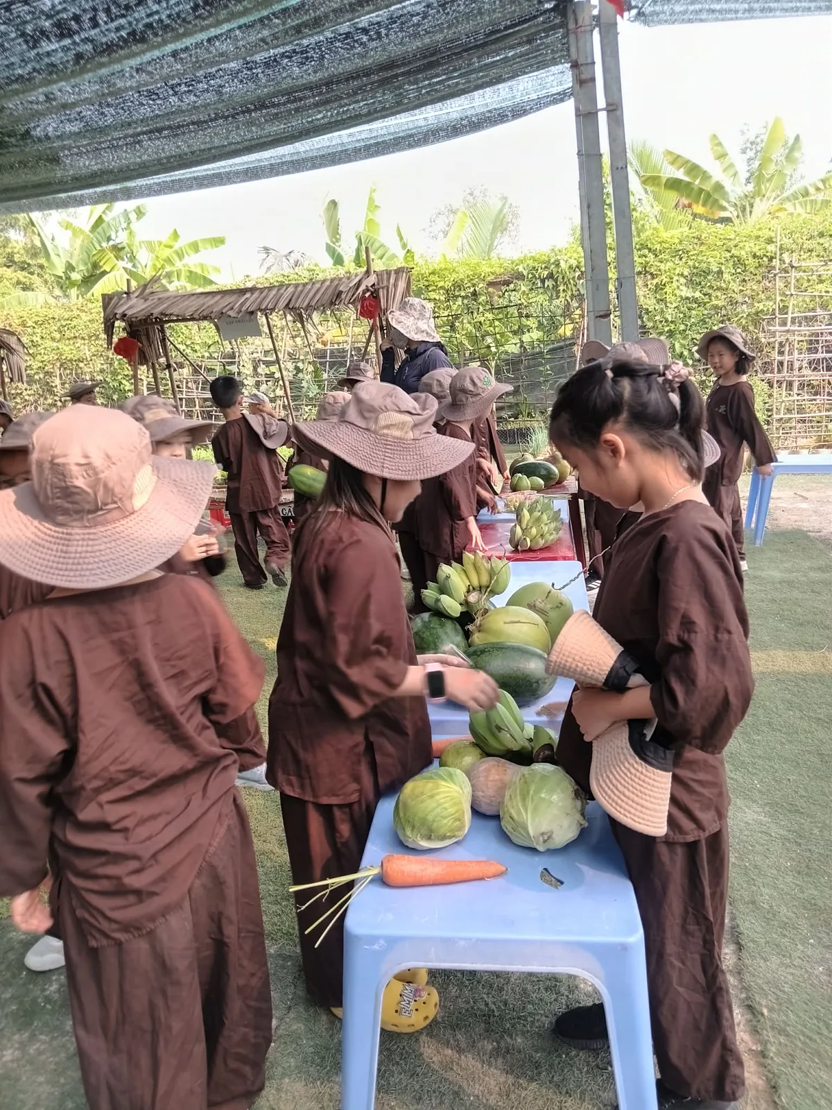 Bé gái ôm nón lá trong không gian chợ quê Nam Bộ tại Dragon Farm