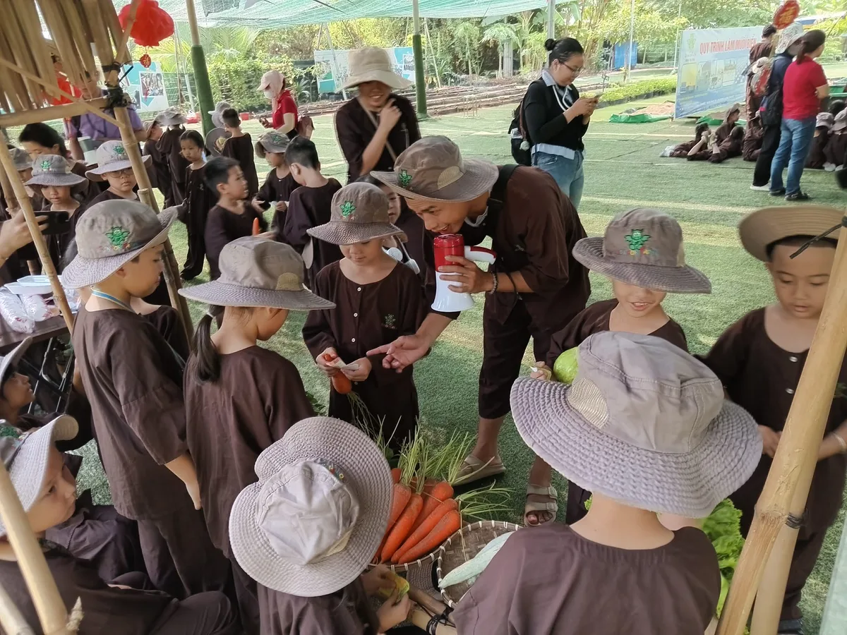 Hướng dẫn viên Dragon Farm cúi xuống hỗ trợ bé chọn cà rốt tại gian hàng chợ quê