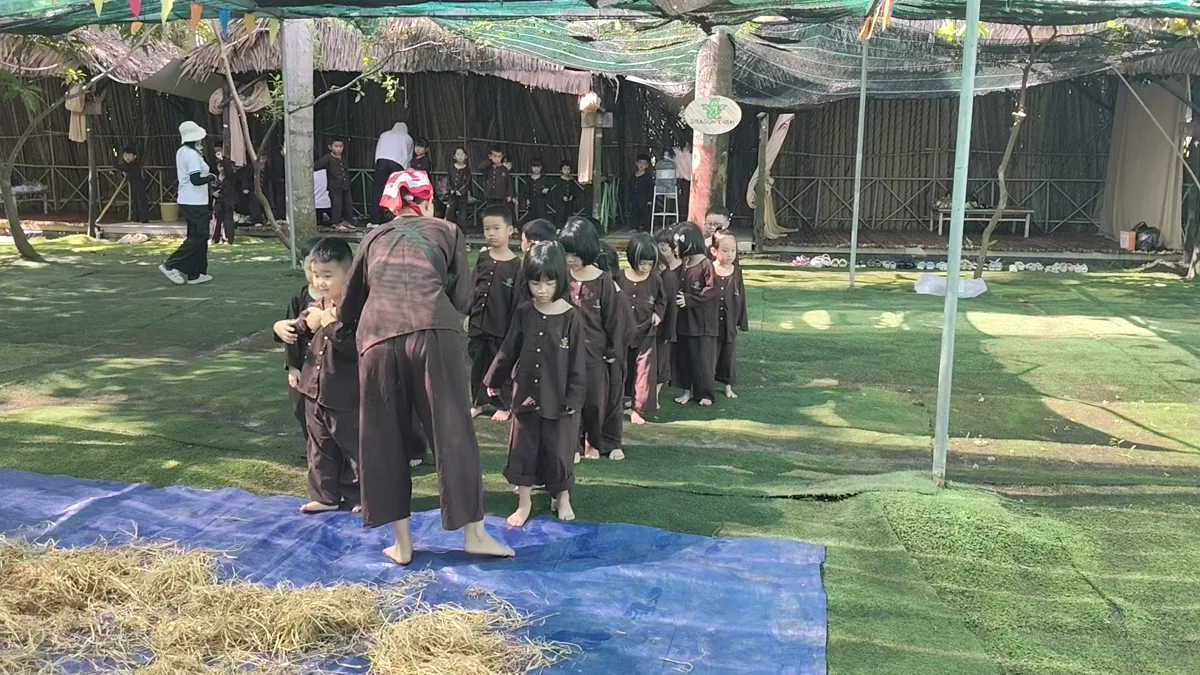 Các bé học sinh mầm non chăm chú lắng nghe hướng dẫn viên giới thiệu luật chơi tìm trứng cút