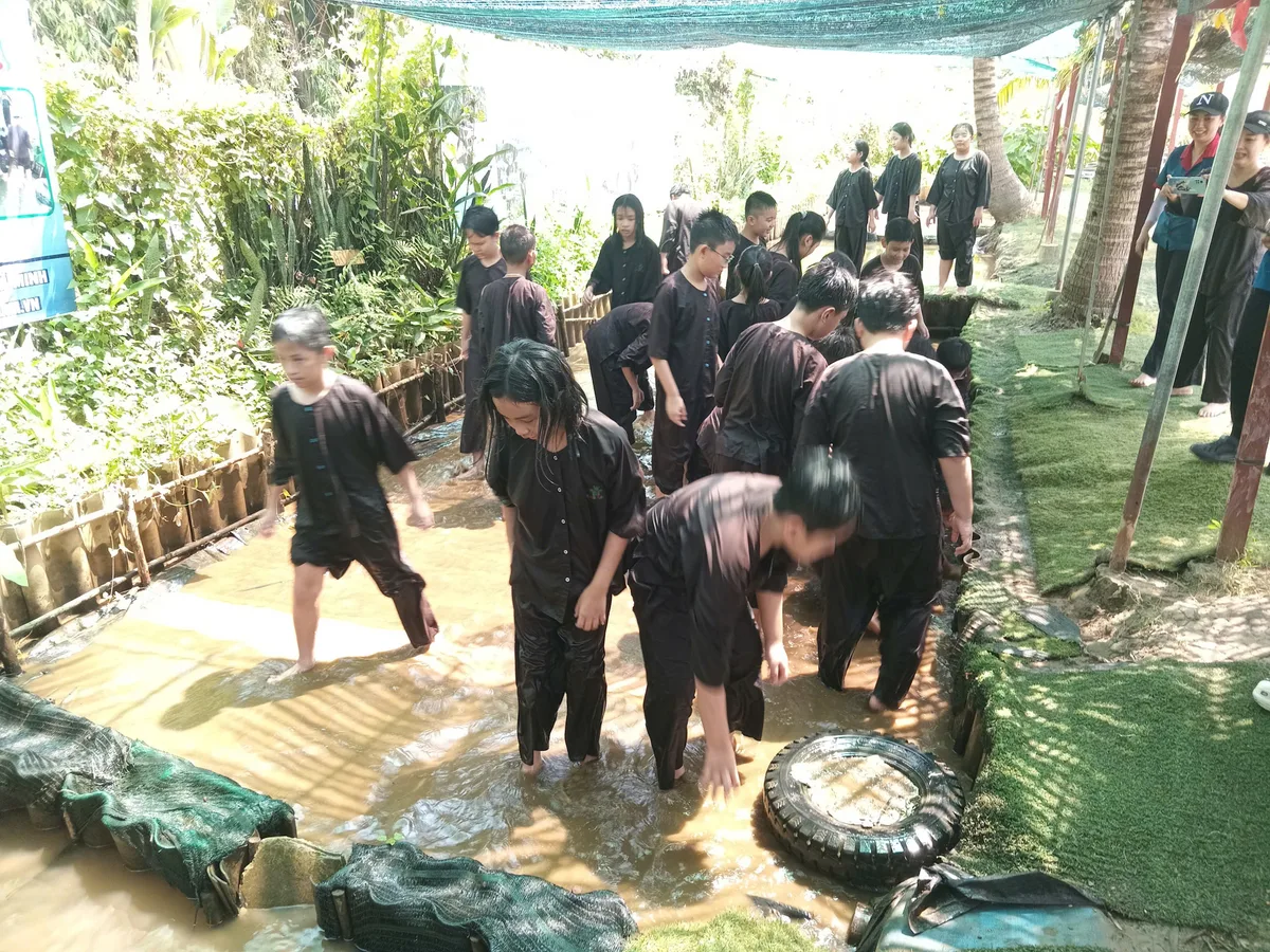 Các bé trong trang phục áo bà ba nâu hào hứng chuẩn bị lội mương bắt cá